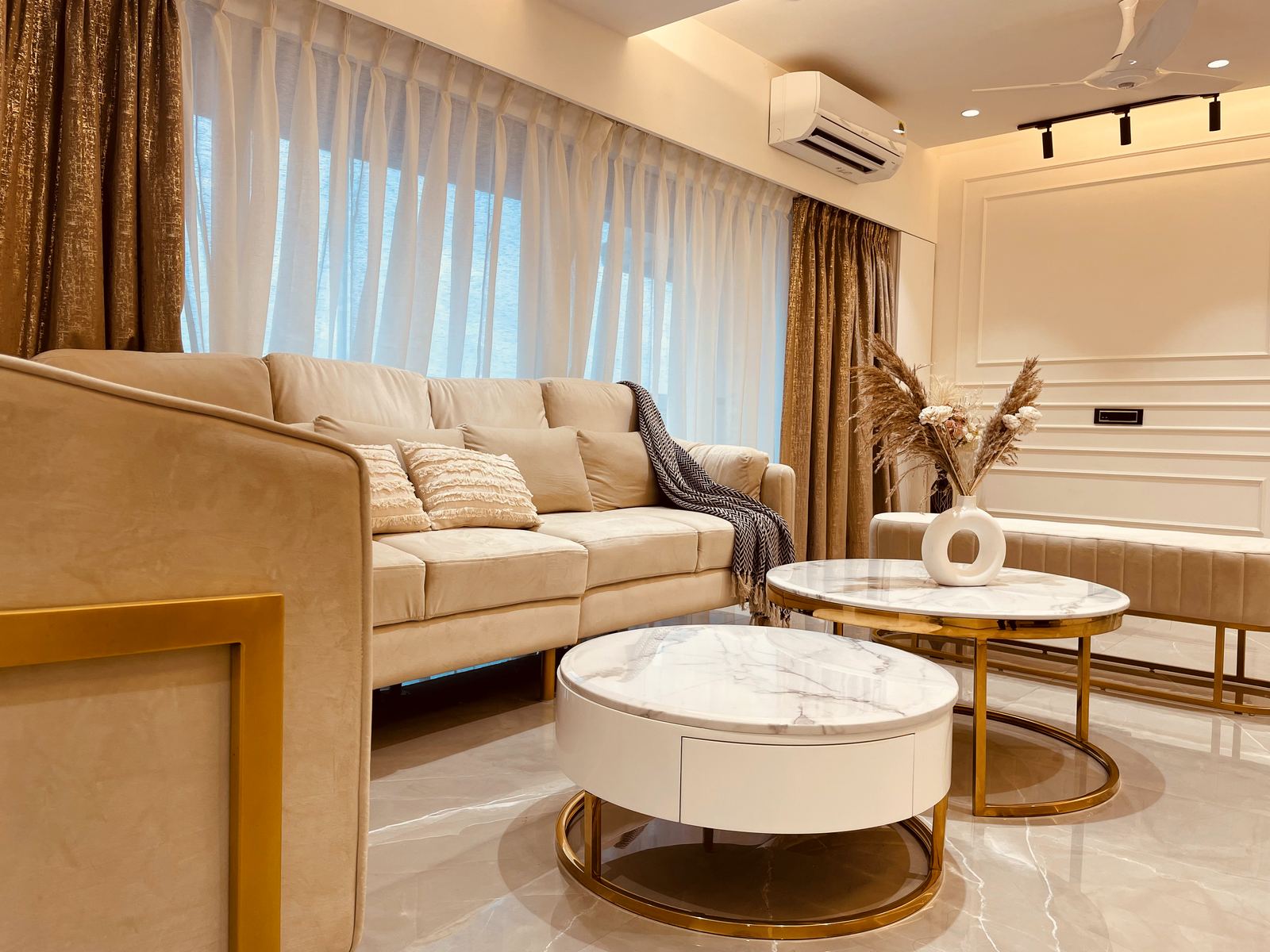Living room with beige sofa, gold curtains and marble coffee tables, real DezignTweak handover Mumbai